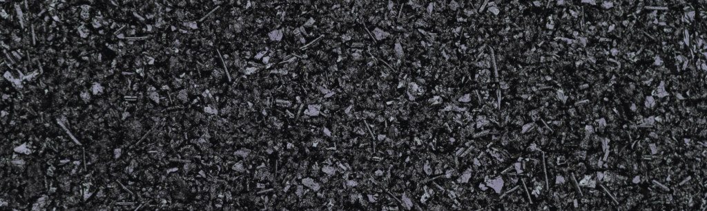 Close-up of a dark, crushed stone surface with small angular gravel fragments, like asphalt texture